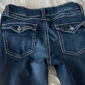Bootcut jeans - Snygga mörkblå jeans från Gina Tricot med kontrasterande vita sömmar. Klassisk femficksmodell med knapp och dragkedja framtill. Perfekta för en avslappnad stil.