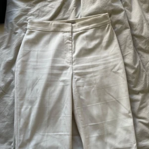 Cremevit kostymbyxa  - Bootcut modell i naturvit/cremevit. Snygg passform. Liten fläck vid insidan av låret, se sista bilden. 