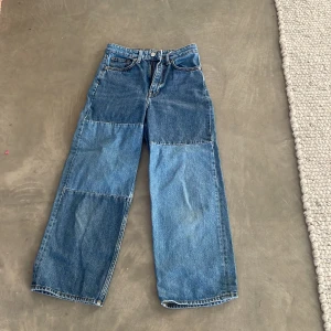 Blå jeansbyxor från Monki - Säljer ett par coola blå jeansbyxor från Monki. De har en hög midja och en avslappnad, wide fit. Byxorna är tillverkade i 100% bomull och har en klassisk femficksdesign. Perfekta för en avslappnad stil.