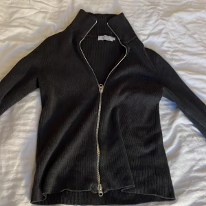 Grå ribbad tröja med dragkedja från Liung - Snygg grå ribbad tröja från Liung by Marcus Larsson med dragkedja framtill. Perfekt för en stilren look , Passar bra till jeans.