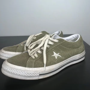 Converse One Star sneakers, Olivgröna - Säljer ett par olivgröna Converse One Star sneakers i mocka med vit sula och snörning. Skorna har den ikoniska stjärndetaljen på sidan och är unisex. Perfekta för en avslappnad stil! Passar de med storlek 43 också! 