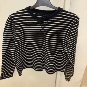 Svart och vit randig tröja från Massimo Dutti - Snygg svart och vit randig tröja från Massimo Dutti. Tröjan har långa ärmar och en rund halsringning med ribbade kanter. Perfekt för en stilren look.