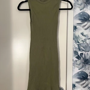 Olivgrön ribbad klänning - Snygg olivgrön ribbad klänning med ärmlös design. Perfekt för en stilren och bekväm look. Klänningen har en tight passform som framhäver figuren. Jätte stretchig i material 