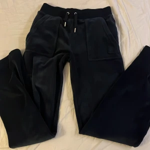 Mörkblåa mjukisbyxor från Juicy Couture - Snygga mörkblåa mjukisbyxor från Juicy Couture i storlek XS. Byxorna har en bekväm passform med snörning i midjan och praktiska fickor med knappar baktill. Inga defekter men har använts 5-10 gånger men frf ett billigt pris. Köpt från raglady från början. 