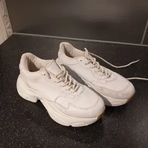 Säljer ett par vita sneakers med hög sula och snörning. Skorna har en modern design med en tjock sula som ger extra komfort och stil. Perfekta för en trendig look. Sparsamt använda, tvättar dem såklart innan frakt.