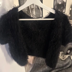 Svart bolero - Säljer en svart bolero med korta ärmar. Toppen har en unik textur som ger en cool look och är perfekt för att sticka ut. Den är mjuk och bekväm att bära. Aldrig använd💖