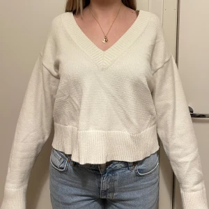 Vit stickad tröja från Bik Bok - Säljer en stilren vit stickad tröja från Bik Bok med v-ringning och långa ärmar. Perfekt för en avslappnad look. Tröjan har ribbade kanter vid ärmslut och nederkant.