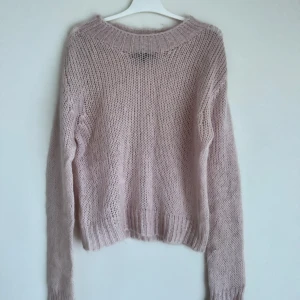 Ljusrosa stickad tröja från Lieblingsstück - Mysig ljusrosa stickad tröja från Lieblingsstück. Perfekt för kyliga dagar med sin mjuka och bekväma passform. Tröjan har långa ärmar och en rund halsringning.