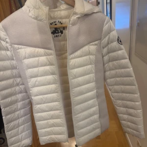 Vit pufferjacka från JOTT - Snygg vit pufferjacka från JOTT med huva och dragkedja. Jackan har ett quiltat mönster och en logotyp på ärmen. Perfekt för kyligare dagar. Väldigt använd därav priset, strl S/XS💕 säljer då den e för lite för mig💕