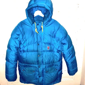 Fjällrävens expedition down lite jacket W - Fjällrävens expedition down lite jacket W i färgen un bleu säljes.  Bästa dunjackan jag har haft och har aldrig frusit i den. Vattenavvisande, vindavvisande och med slitstarkt tyg. Skön huva med dragsko. Dragsko även i midja och nertill. Rymliga fickor samt innerficka  Den är märkt strl XS men dessa jackor är extremt stora i storleken. Motsvarar snarare strl  S/M. Jag är 168 och väger 68 kg och mig passar den perfekt.   Den hade mått bra av en kemtvätt, därav priset.  Finns i centrala Lund.  