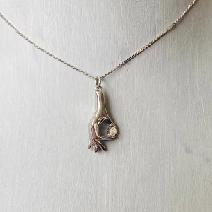 Silverhalsband med handformad berlock - Unikt silverfärgat halsband med en cool berlock formad som en hand som håller en liten sten. Kedjan är tunn och elegant, vilket gör att berlocken verkligen står ut. Perfekt för att ge en edgy touch till vilken outfit som helst! Okänd metall 