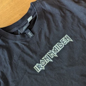 Svart Iron Maiden t-shirt - Säljer en svart Iron Maiden t-shirt i storlek M. Den har bandets logga på framsidan och ett stort backtryck skulle säga den större i storleken så M 