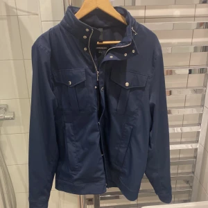 J.lindeberg fieldjacket - Helt otroligt snygg jacka från J.lindeberg. Jag köpte den förra våren och har nu tyvärr vuxit ur den så därför den säljs. Finns inte en enda lite skråma! Helt felfri! Som ny!