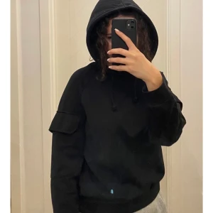 Hoddie med armfickor - Svart Hoddie med fickor på armarna från Gina Tricot i storlek XS. Knappt använd och är i bra skick. 