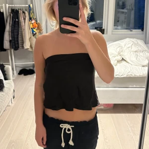 Svart axelbandslös topp - Säljer en stilren svart axelbandslös topp från Zara. Toppen är tight och croppad, vilket ger en snygg och modern look. Har tecken på användning. storlek M. liten i storleken