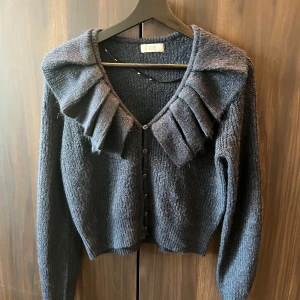 Stickad tröja - Mycket fin mörkblå stickad tröja i ett väldigt skönt material, knappar framtill. Oanvänd, 100kr.