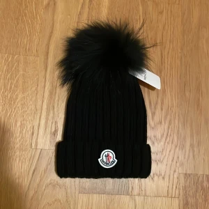 Ny Beanie Moncler mössa svart med avtagbar fin tofs modern och populär modell  - Ny Beanie Moncler mössa svart med avtagbar fin tofs  Mössan är både modern och populär modell 