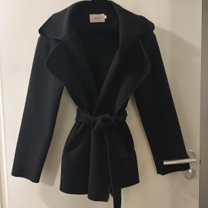 Svart kappa - Säljer denna supefina kappa i storlek 34 som är slutsåld från nelly. Säljer då jag har flera kappor och inte använder denna. Den är i fint skick! Köpt för ca 800 kr🩷