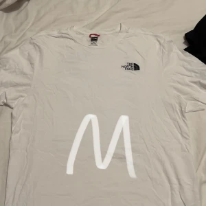 Vit t-shirt från The North Face - Säljer en vit t-shirt från The North Face i storlek M. Den har en liten logga på bröstet och ett stort tryck med bergsmotiv på ryggen. Perfekt för vardagsbruk eller äventyr! 🏔️