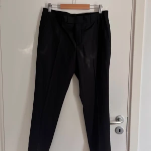 Svarta kostymbyxor - Säljer ett par stilrena svarta kostymbyxor i storlek 32-32. Byxorna har en klassisk passform och är i nyskick.