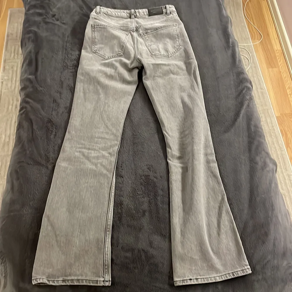 Säljer ett par snygga grå bootcut jeans från Gina Tricot i storlek 32. De är i bra skick, använda endast 2-3 gånger och har en klassisk femficksdesign med knapp och dragkedja framtill. Perfekta för både vardag och fest! 🖤. Jeans & Byxor.