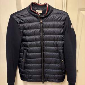 En navy blue Moncler Cardigan i utmärkt skick. Den är inköpt från en leverantör så kvitto och annat följer ej med. Storlek: S  Skick: 4/5 (nästan helt ny)