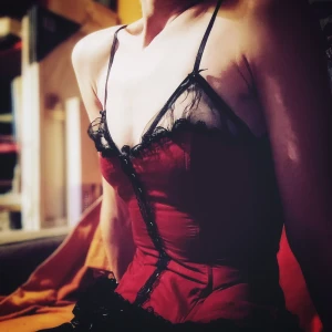 Röd korsett med spetsdetaljer - Säljer en elegant röd korsett med svarta spetsdetaljer. Den har smala axelband och snörning där bak för en figurnära passform som ger en snygg siluett. Perfekt för festliga tillfällen!