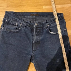 Nudie grim tim - Säljer nu dessa mörk blåa Nudie jeans i model grim Tim | Storlek: 33 24 men sitter lite mindre. Skulle säga w 30-31 l 30-32. Ta gärna hjälp av måtten på bilderna för att säkerställa storleken | Pris 599 då det är i nyskick!