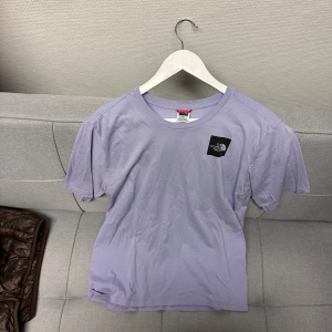 Ljuslila t-shirt från The North Face - Säljer en skön ljuslila t-shirt från The North Face i storlek M. Den är kortärmad och har en klassisk passform med loggan tryckt både fram och bak. Sparsamt använd och i bra skick. 