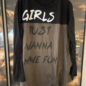 Svart och brun långärmad tröja med text - Cool och avslappnad långärmad tröja i svart och brun med texten 'Girls Just Wanna Have Fun' i vitt och svart. Perfekt för en chill dag eller en avslappnad kväll med vänner. Tröjan har en rund halsringning och är gjord i ett mjukt material för extra komfort.