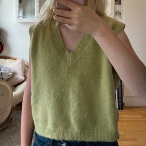 Grön stickad väst - Säljer en superfin grön stickad väst med v-ringning. Perfekt för lager-på-lager under hösten eller våren. Den är mjuk och bekväm. Litte nopprig annars bra kvalitet!