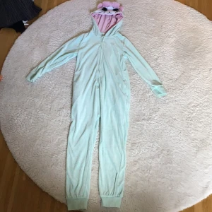 Turkos one-piece, mus. Kappahl - Säljer en turkos och rosa onepiece. Mus med rosett, öron, morrhår, nos och ögon. Dragkedja på framsidan, fickor. Kappahl storlek 134/140-hittar ingen lapp med storlek.