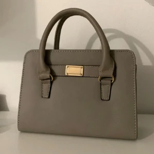 Grå handväska  - Från Ur & Penn Har inga defekter förutom att den har avklippta band (bild 3) men inget som syns eller påverkar😊