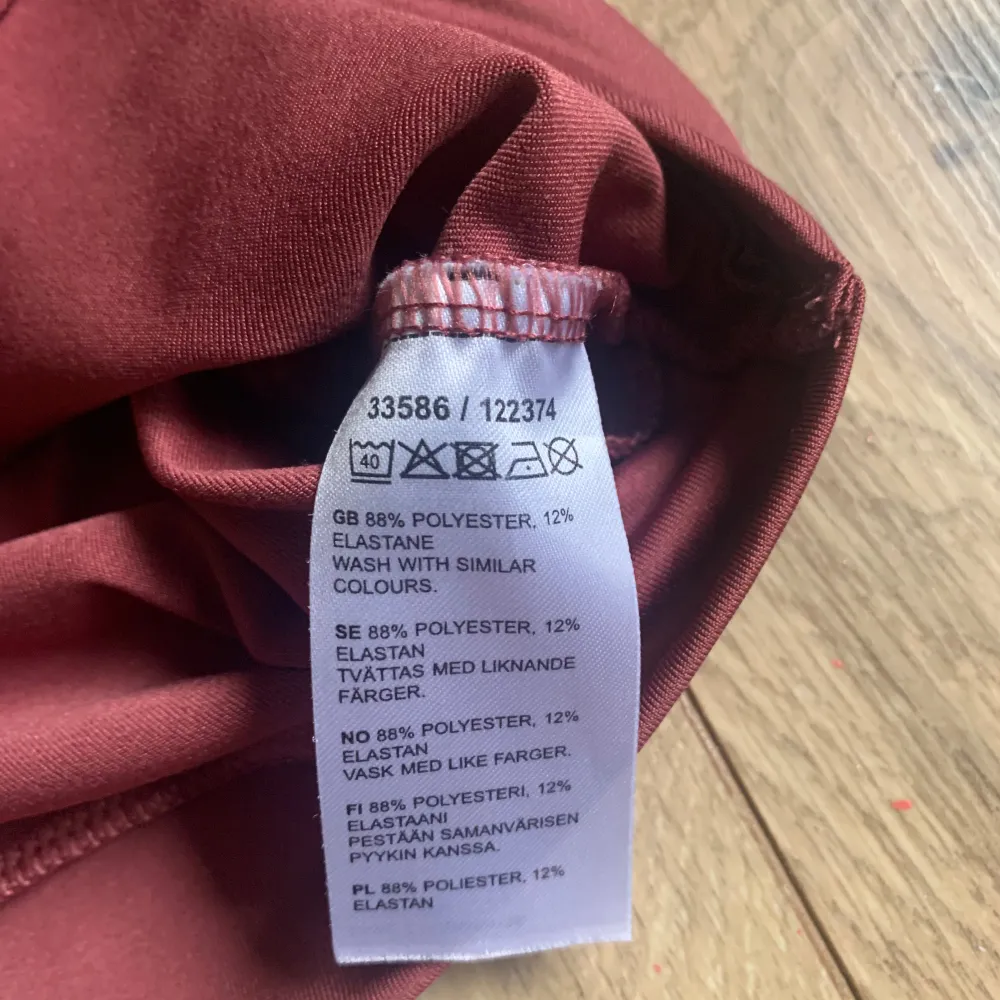 Säljer en snygg röd ärmlös topp i storlek M. Den är gjord av 88% polyester och 12% elastan, vilket gör den både bekväm och stretchig. Toppen har en cool twist-detalj framtill som ger den en unik look. Perfekt för träning eller en avslappnad dag ute!. Toppar.