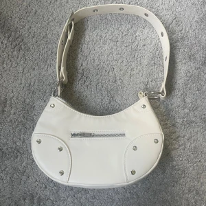 Superfin handväska - Superfin handväska med coola detaljer, passar perfekt både till vardags och fester. Väskan är i nyskick 