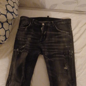 Svarta jeans från Dsquared2 - Snygga svarta jeans från Dsquared2 med en cool tvättad look och slitna detaljer. De har en knappgylf och klassisk femficksdesign. Perfekta för en trendig stil. Passar mig som normalt sett bär storlek M i byxor perfekt. Så du som bär M ska den passa. Står dock stryk 44