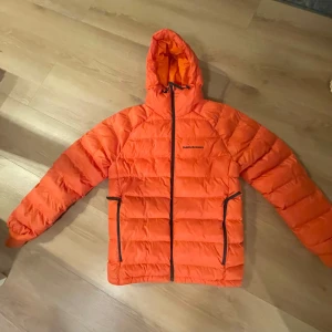 Orange dunjacka från Peak Performance - Säljer en snygg orange dunjacka från Peak Performance.  TOMIC INSULATED HOOD JACKET. Perfekt för kyliga dagar! 🍂 Jackan har lagats inuti en ficka, se bild. Lite missfärgning vid ärmslut, syns knappt när den är på (bra fläckborttagning kanske fungerar då jag endast tvättat med tvättmedel). 