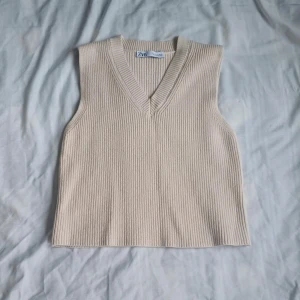 Beige ribbad väst från Zara - Säljer en stilren beige ribbad väst från Zara. Passar utmärkt till både vardag och mer uppklädda tillfällen.