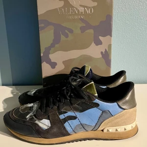 Valentino Rockrunners - Snygga Valentino Rockrunners med ett coolt camouflagemönster i blått, marinblått och beige. Skorna har snörning och en unik design med nitar på hälen. Kom gärna med frågor eller prisförslag:)