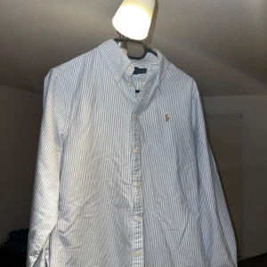 Randig skjorta från Ralph Lauren - Skjorta från Ralph Lauren i blå och vit randigt mönster. Köpte den i somras men den har endast legat i min garderob då den är en storlek för liten. Skicket är alltså 10/10! Bara att höra av dig för frågor eller mer bilder! Nypris typ 1 000kr