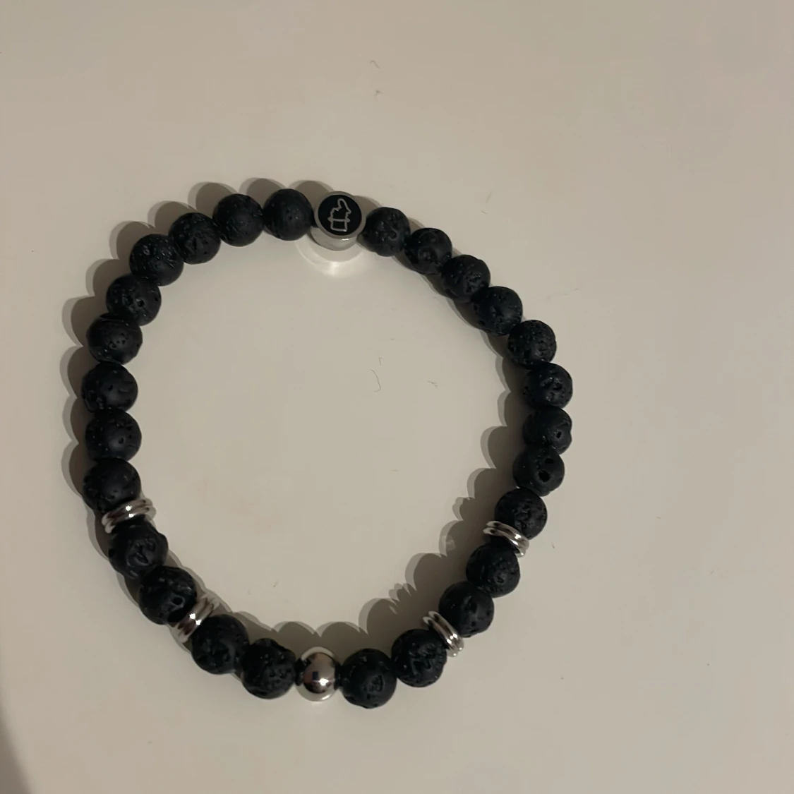 Svart armband med lavastenar och silverdetaljer från edd.