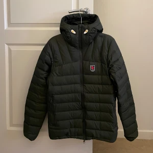 Fjällräven jacka - Säljer en grön dunjacka från Fjällräven, 1974 Expedition Series. Perfekt för kalla dagar med sin pufferdesign som håller värmen bra. Den har inte använts mycket. Storlek XS men passar som S.