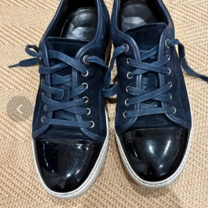 Mörkblå sneakers från Lanvin -  Intressekoll på mina Snygga mörkblå sneakers från Lanvin med snörning och en glansig tå i svart. Skorna har en vit sula med Lanvin-logotypen på undersidan. Perfekta för en stilren look. Allt og ingår hör av er om ni vill köpa ! Uk 7 tvättas innan ja skickar dem 2700 minsta pris 