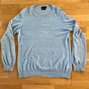 Oscar Jacobson tröja  - Säljer en elegant ljusblå tröja från Oscar Jacobson . Tröjan har en klassisk rund hals och långa ärmar med ribbade muddar. Perfekt för en stilren och bekväm look. Tröjan är i linne material och perfekt nu till våren. Nypris: 1799 kr