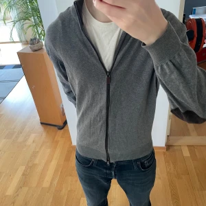 Massimo Dutti Full Zip cardigan  - Säljer en stilren Full Zip Cardigan från Massimo Dutti. Cardiganen är i storlek L men sitter som en M. Den är i en fin Mörkgrå färg som passar till allt, den har även fina detaljer på ärmarna som får den att se mer gammaldags och passar perfekt till ”old money” stilen. Hör gärna av er vi frågor eller funderingar!!