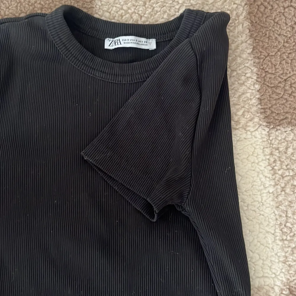Säljer en stilren svart ribbad t-shirt från Zara. Den har en klassisk rund hals och korta ärmar, perfekt för en enkel och snygg look. Passar bra till både jeans och kjol. 🖤. T-paidat.