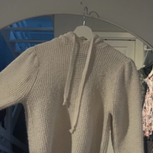 Vit stickad hoodie från Primark - Mysig vit stickad hoodie från Primark med en skön huva och långa ärmar. Perfekt för kyliga dagar när du vill vara både bekväm och stilren. Den har en avslappnad passform och är lätt att matcha med olika outfits.