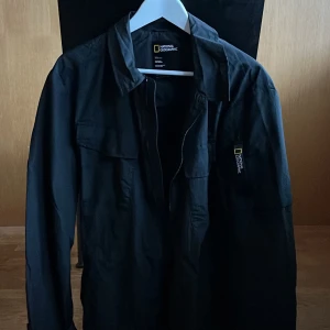 Svart jacka från National Geographic - Säljer en stilren svart jacka från National Geographic. Jackan har en dragkedja framtill och är långärmad. 