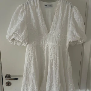 Vit klänning från Zara - Säljer en superfin vit klänning från Zara med puffiga kortärmar och djup v-ringning. Perfekt för sommarens tillfällen! 💕