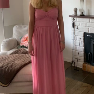 Rosa långklänning - Säljer min balklänning från 9an. Endast använd vid ett tillfälle. Jag är 166 och den är lång för mig men jag hade ett par klackar och då gick det bra. Den har två smala band man kan haka på om man vill. Super fin men får inte amvändning för den något mer. Någon tråd är lös men det ser man inte om man inte letar efter den. Skriv om frågor. 